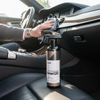 Planet Car Care CarPro InnerQD interior quick detailer spray bottle on a car seat with a person cleaning the dashboard.