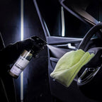 Planet Car Care CarPro InnerQD interior quick detailer spray being applied to a car steering wheel with a microfiber cloth