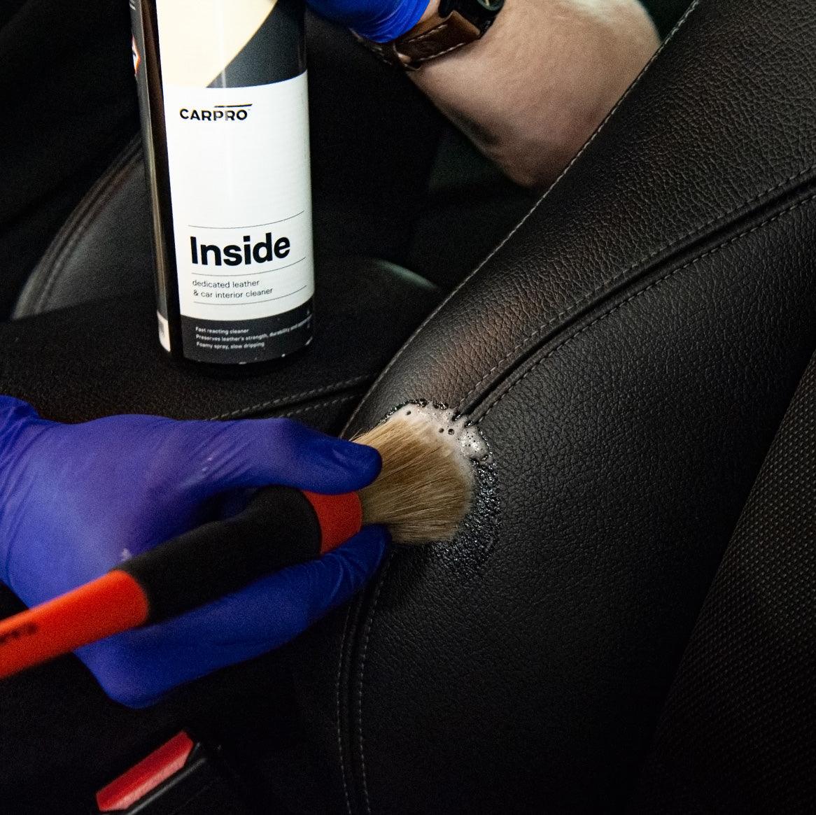 Planet Car Care CarPro Inside cleaner being applied to a black leather car seat with a detailing brush