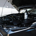 Planet Car Care CarPro Perl plastic and rubber dressing bottle placed inside a car engine bay for maintenance
