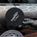 Planet Car Care CarPro 130mm rayon glass polishing pad held in a gloved hand for automotive detailing