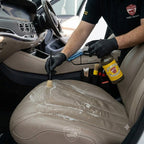 Planet Car Care professional using ClearPro APC and a detailing brush to clean a perforated leather car seat.