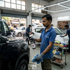 Planet Car Care technician using EraseX Panel Preparation Spray to clean a car surface in a professional workshop.