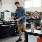 Planet Car Care PPF slip solution spray bottle on a workbench with a technician applying film to a black car