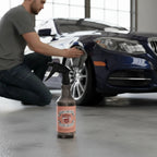 Planet Car Care PPF Slip Solution 750ml spray bottle on a garage floor with a technician applying film to a car