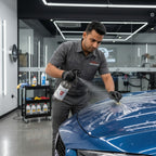 Planet Car Care technician applying PPF tack solution to a blue car hood in a professional detailing studio