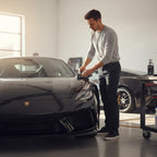 Planet Car Care professional applying Puris Jade Black Dress Pro ceramic coating to a black luxury sports car