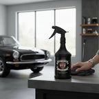 Planet Car Care TarMac tar and glue remover in a black spray bottle on a workbench with a car in the background.