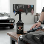 Planet Car Care TarMac tar and glue remover spray bottle being used to clean a car surface in a professional garage