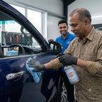 Man using Planet Car Care Eco Gloss waterless wash spray and microfiber cloth to clean a dark blue car door